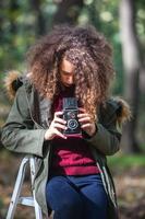 menina adolescente com câmera retro tirando fotos na natureza