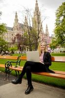 jovem mulher com laptop no banco do parque foto