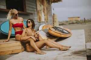 mulheres jovens de biquíni sentadas na cabana de surf em uma praia em um dia de verão foto