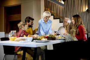 família feliz jantando com vinho tinto em casa foto