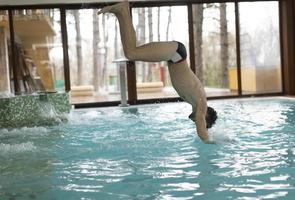 jovem pulando na piscina foto