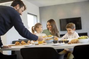 jovem família feliz conversando enquanto toma café da manhã na mesa de jantar foto