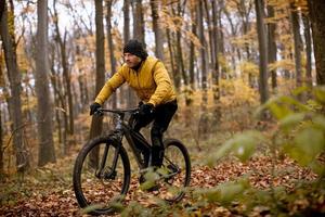 jovem andando de bicicleta pela floresta de outono foto