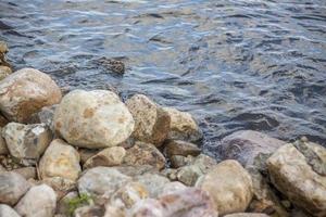 papel de parede com pedras à beira do rio e água. dê um passeio no parque em um dia de verão e admire a bela paisagem. foco seletivo, papel de parede. foto