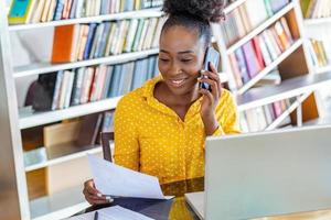 mulher de negócios atraente, falando ao telefone, mulher afro-americana no seminário de treinamento, líder de negócios feminina indo a papelada verdadeira em seu escritório foto