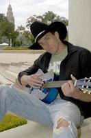 bonito jovem cowboy tocando violão no parque. foto