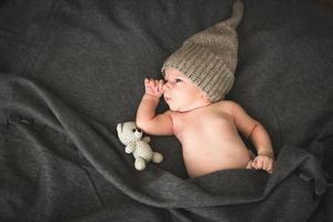 bebê recém-nascido com um brinquedo deitado ao lado do ursinho de malha foto