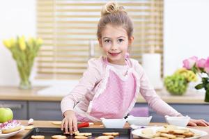 menina bonitinha preparando biscoitos na cozinha foto