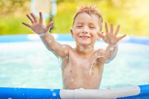 menino bonito nadando e brincando em uma piscina no quintal foto