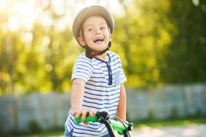 menino feliz de 3 anos se divertindo andando de bicicleta foto