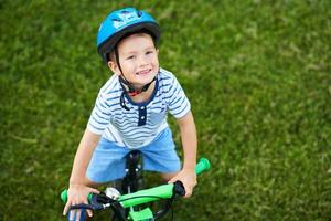 menino feliz de 3 anos se divertindo andando de bicicleta foto