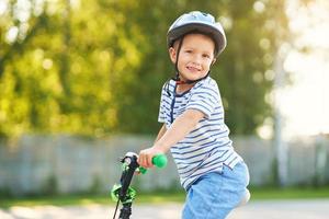 menino feliz de 3 anos se divertindo andando de bicicleta foto