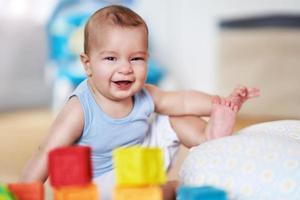 lindo menino sorridente sentado no chão na sala de estar foto