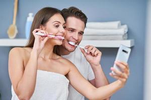 retrato de casal jovem feliz escovando os dentes no banheiro foto
