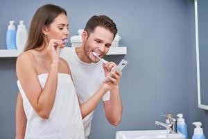 retrato de casal jovem feliz escovando os dentes no banheiro foto