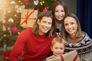 linda família com presentes sobre a árvore de natal foto