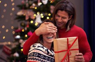 lindo casal adulto com presente sobre a árvore de natal foto