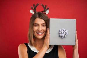 mulher adulta feliz com presente de natal sobre fundo vermelho foto