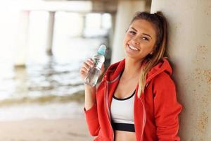 mulher com garrafa de água depois de correr na praia foto