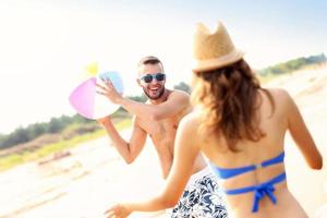 jovem casal brincando com uma bola na praia foto