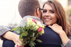 mulher com flores dando abraço em seu homem foto