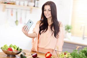 mulher feliz preparando salada na cozinha moderna foto