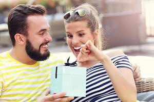 casal feliz com presente sentado do lado de fora foto