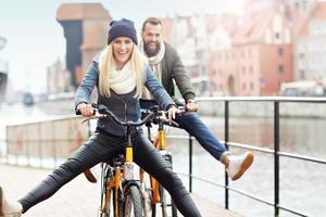 jovem casal andando de bicicleta e se divertindo na cidade foto