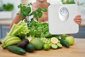 mulher adulta saudável com comida verde na cozinha foto