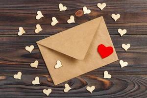 envelope de carta de amor com coração vermelho sobre fundo de madeira foto