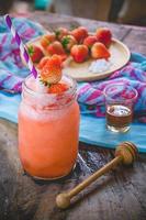 suco de smoothie de morango, no topo de mel saboroso para o verão na mesa de madeira, suco de água doce para a saúde foto