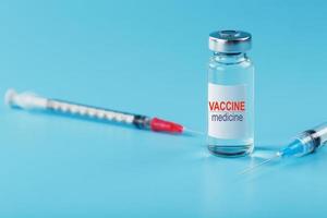 ampola de medicamento de vacina com uma seringa em um fundo azul. foto