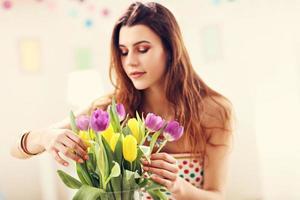 mulher atraente organizando flores de tulipas em vaso foto