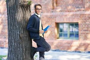 estudante do sexo masculino no campus estudando ao ar livre foto