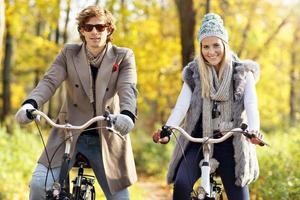 casal feliz em bicicletas na floresta durante o outono foto