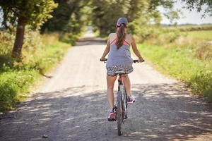 jovem mulher feliz em uma bicicleta na zona rural foto