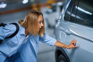 retrato de jovem com carro arranhado no estacionamento subterrâneo foto