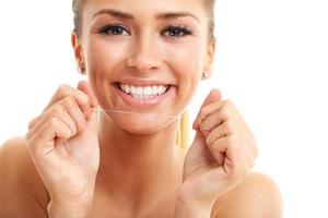mulher adulta passando fio dental nos dentes isolada no branco foto