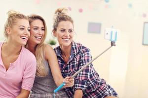 três mulheres bonitas relaxando em casa e tirando selfie foto