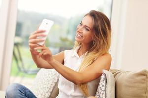 mulher no sofá da sala tomando selfie foto