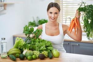 mulher adulta saudável com comida verde na cozinha foto