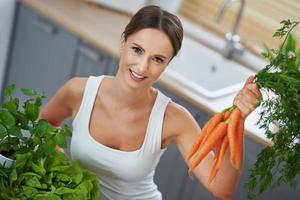 mulher adulta saudável com comida verde na cozinha foto