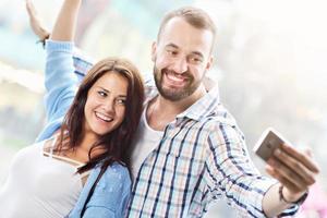 casal feliz usando smartphone na cidade em dia chuvoso foto
