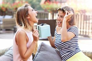 uma foto de duas amigas fazendo um presente de aniversário surpresa