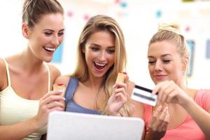 três belas jovens fazendo compras online foto