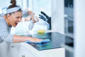 jovem mulher limpando sujeira na cozinha foto