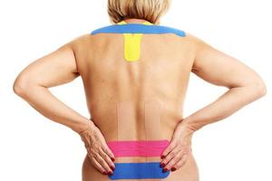 imagem mostrando a fita especial de fisioterapia colocada nas costas lesionadas sobre fundo branco foto