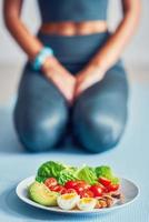 mulher adulta comendo almoço saudável e sentado no tapete de ioga foto
