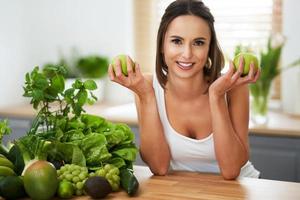 mulher adulta saudável com comida verde na cozinha foto