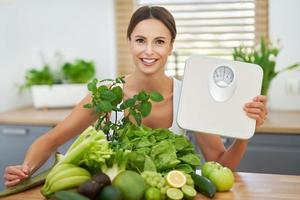 mulher adulta saudável com comida verde na cozinha foto